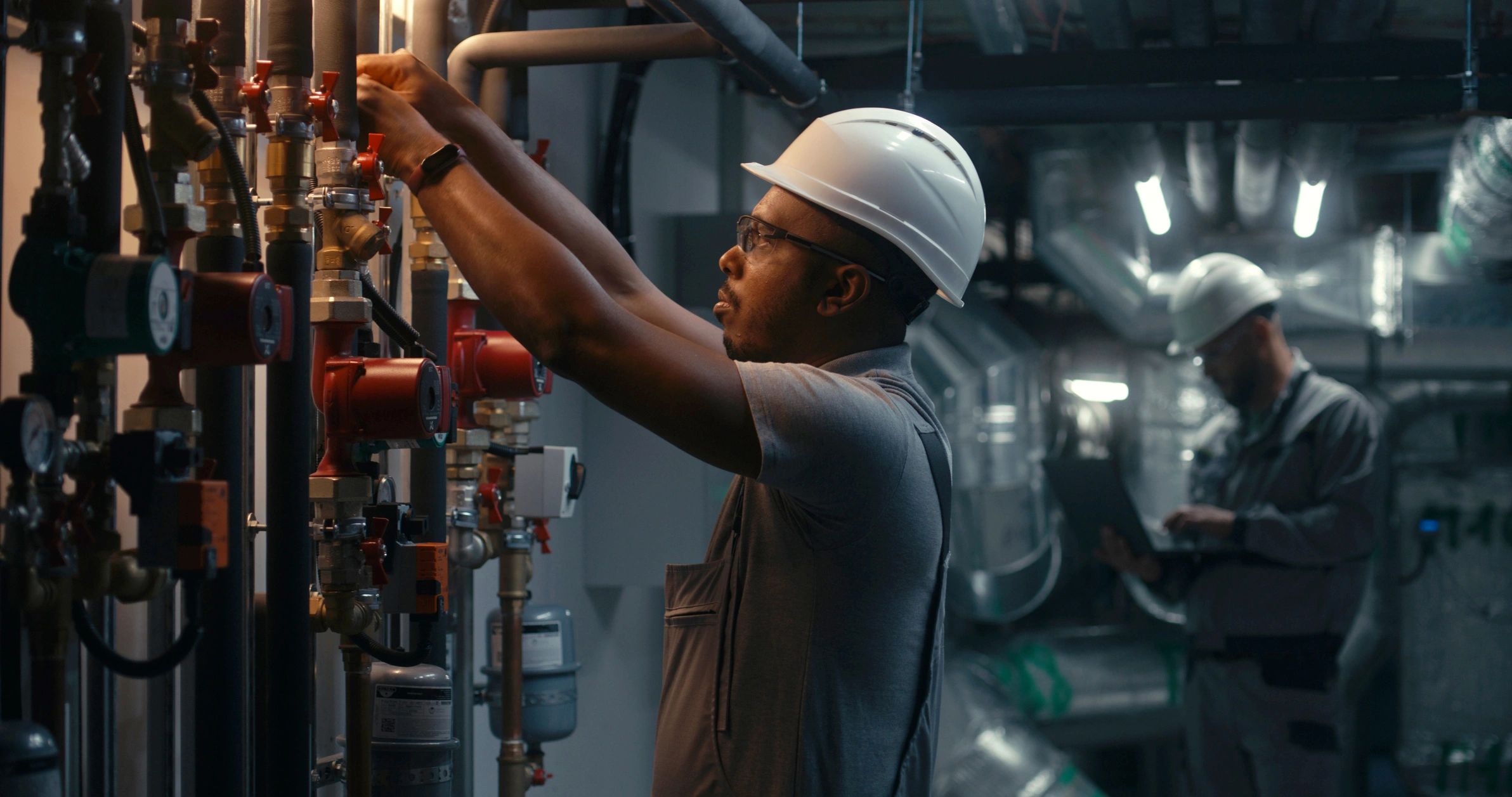 Technician inspecting industrial equipment with safety gear